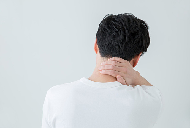 首の後ろをおさえる男性