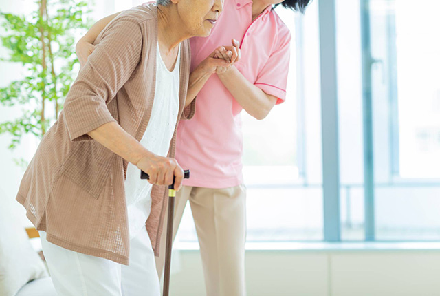 支えられて歩く高齢者